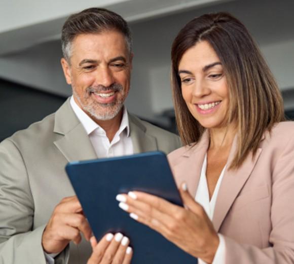 Man and woman looking at a tablet smiling