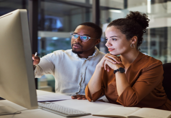 Man and woman looking at a desktop screen 